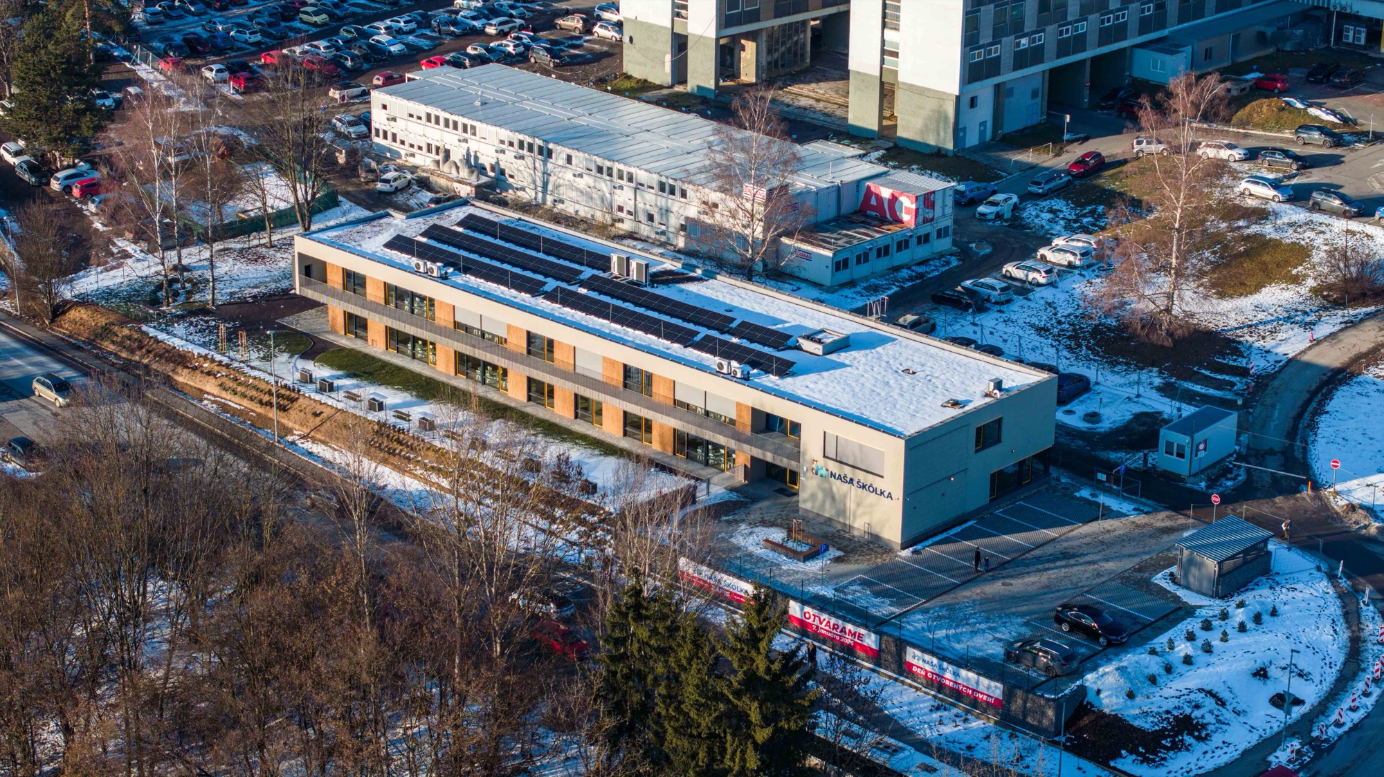 Budova materskej školy so solárnymi panelmi v zime z dronu