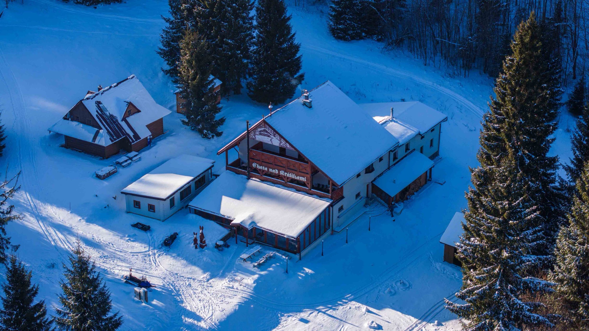 Zasnežená horská chata medzi smrekmi z dronu